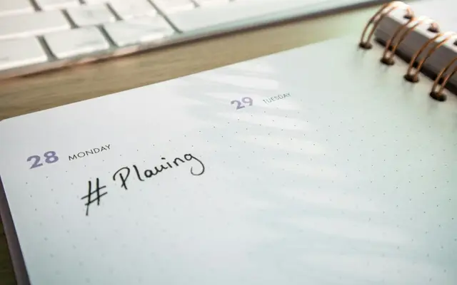 Agenda de papel aberta ao lado do teclado, para marcar visitas a imóveis