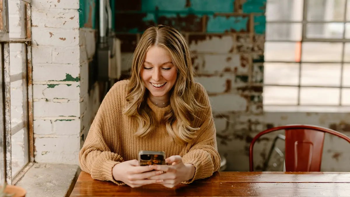 Mulher à mesa olhando o celular, conversando com um lead de imóvel no WhatsApp