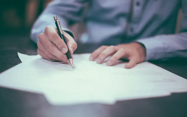 Homem fazendo anotações no papel, no controle de locação da imobiliária