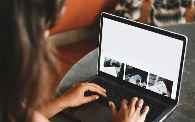 Mulher usando notebook na mesa, comparando portais imobiliários e anúncio próprio