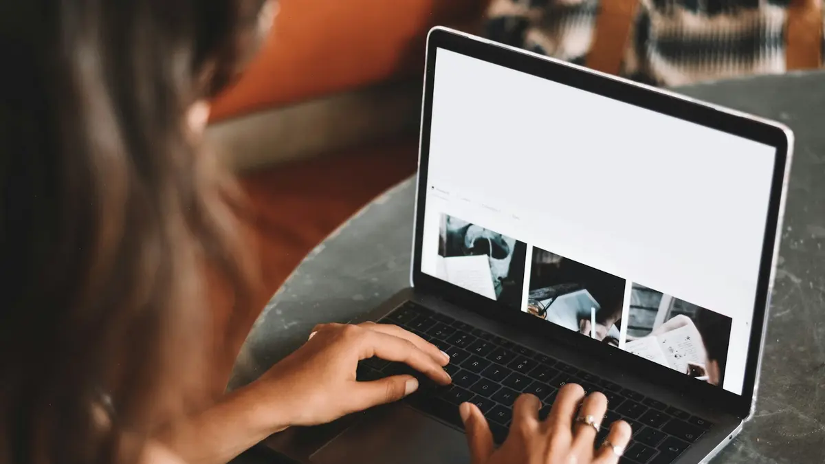Mulher usando notebook na mesa, comparando portais imobiliários e anúncio próprio