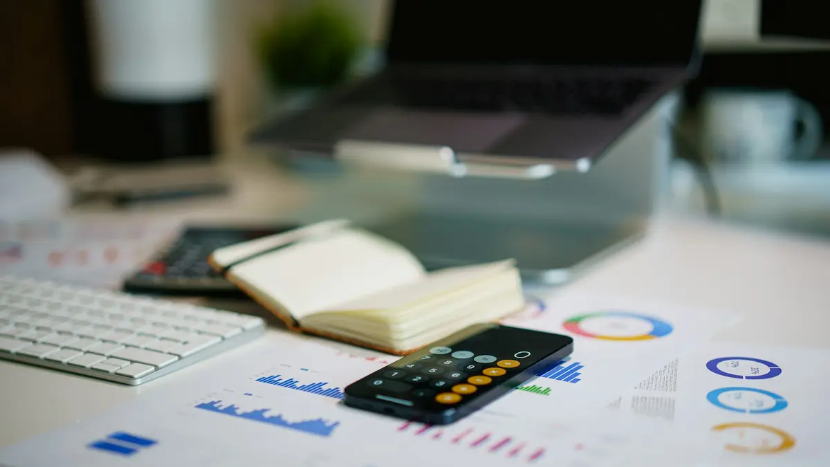 Escritório com celular e gráficos financeiros, calculando quanto custa um CRM imobiliário