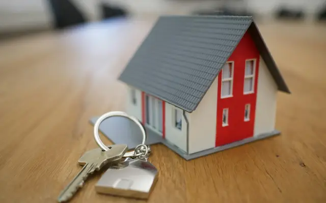 Miniatura de casa de madeira sobre a mesa, entre a gestão de aluguéis e a venda de imóveis