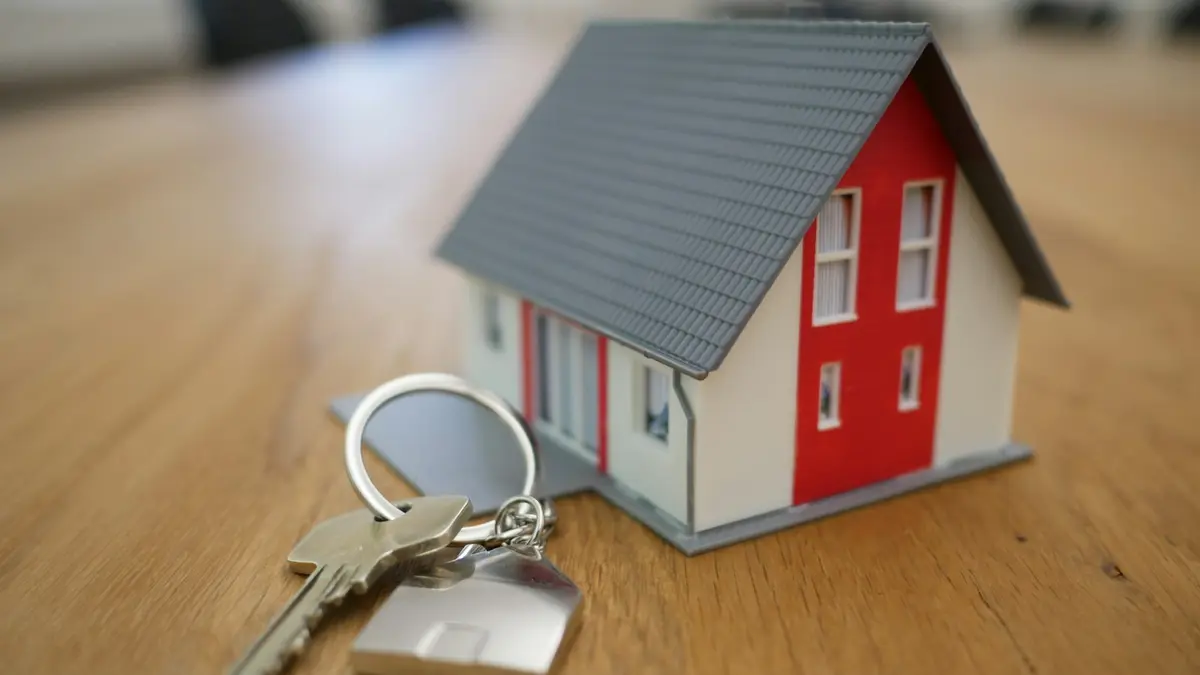 Miniatura de casa de madeira sobre a mesa, entre a gestão de aluguéis e a venda de imóveis