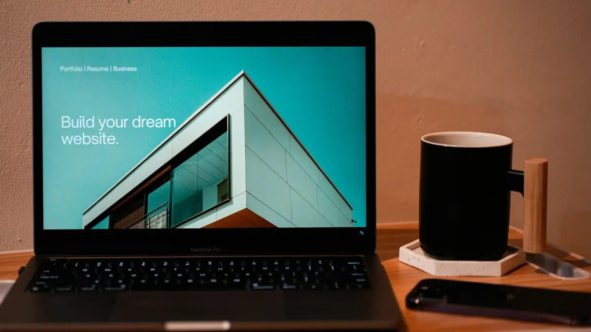 Notebook aberto sobre mesa de madeira, mostrando o site da imobiliária