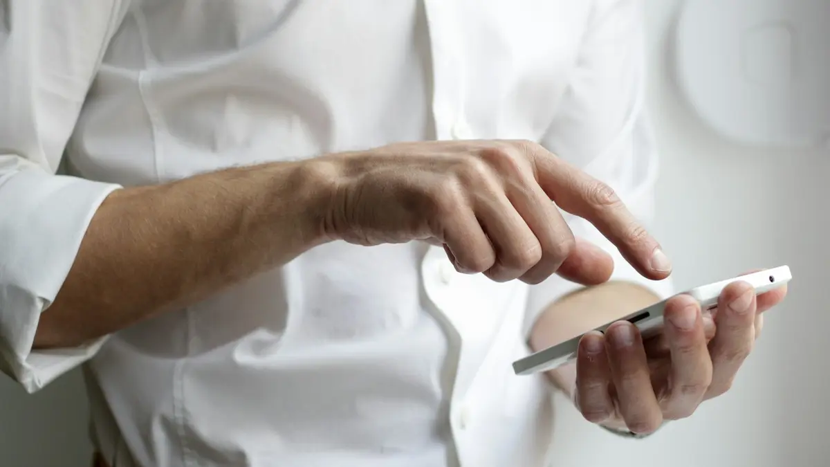 Pessoa segurando o celular, decidindo entre o WhatsApp oficial e o comum na imobiliária